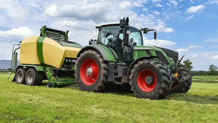 green tractor hauling harvesting equipment